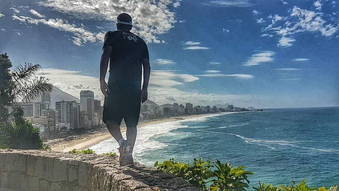 Edu caminhando diante da paisagem do Rio de Janeiro